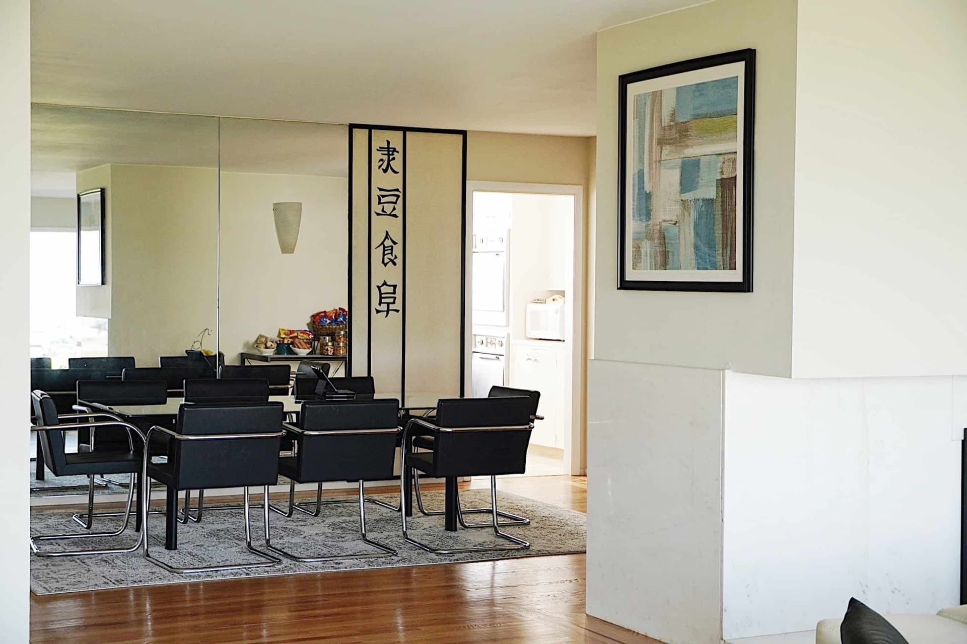 Dining room with a long table, black leather chairs and a mirrored wall