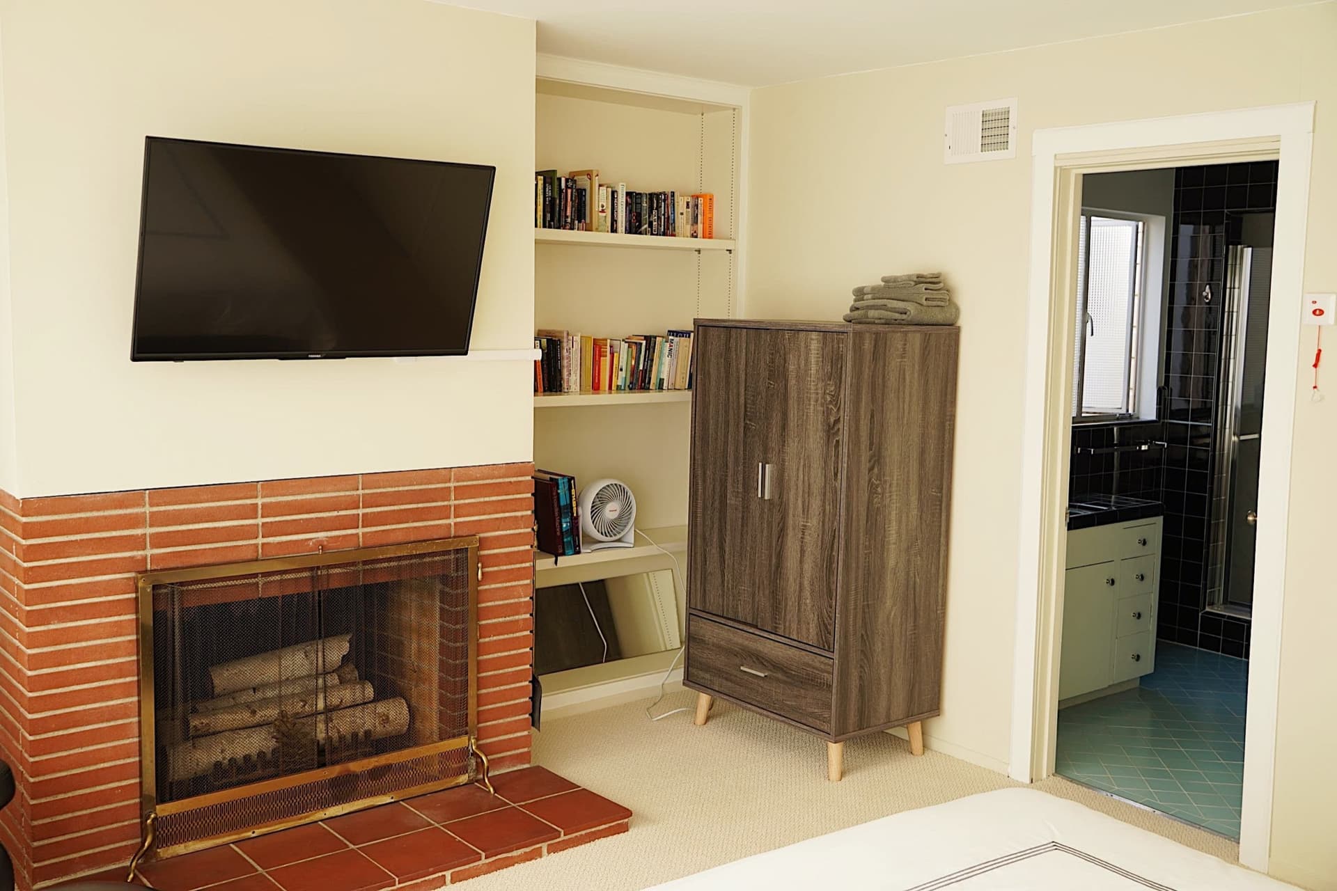 Guest room with a brick fireplace, bookshelves and an ensuite bathroom