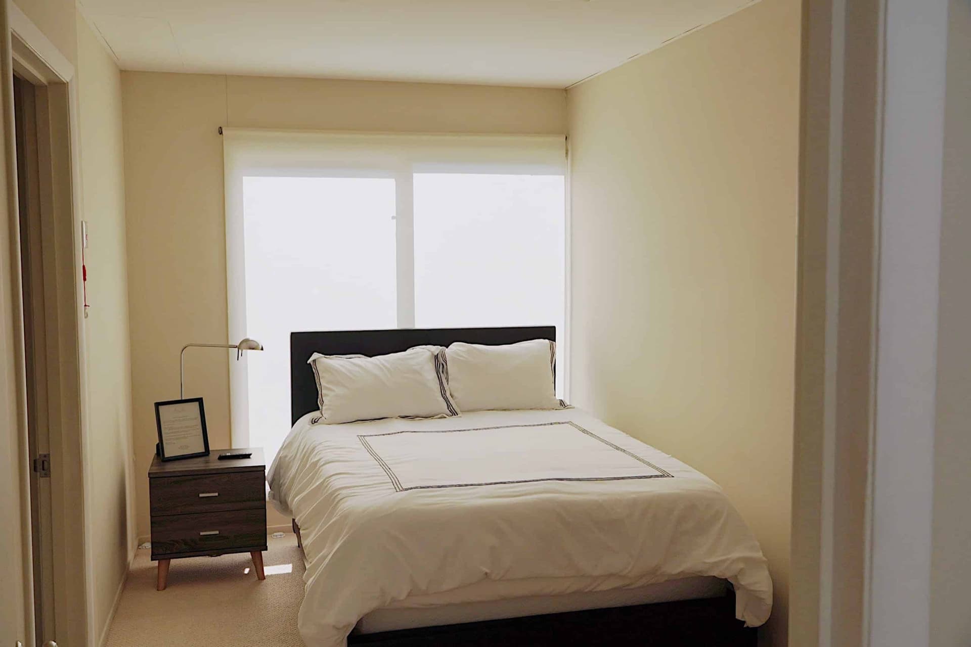 Quiet guest room with a queen bed and a softly shaded window